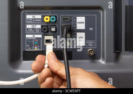 Man collega il cavo Internet alla TV. Foto Stock