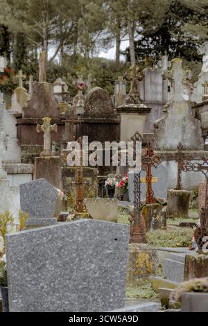 Cimitero affollato di croci di ferro arrugginite e lapidi in pietra in un giorno grigio. Foto Stock