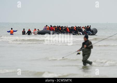 La gente pensata come migranti si tuffò in mare per salire a bordo di una piccola barca a Gravelines, in Francia. Data foto: Venerdì 10 ottobre 2025. Foto Stock