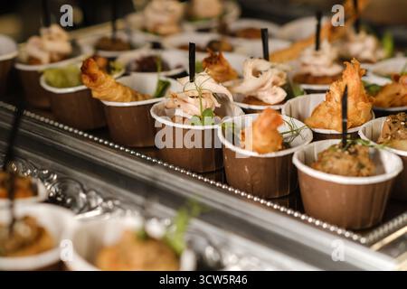 Deliziosi stuzzichini serviti in eleganti tazze in occasione di un incontro di festa la sera, che mostrano una varietà di consistenze e sapori Foto Stock