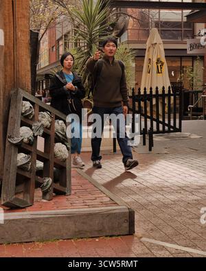 Questo scatto di stile di vita cattura una coppia in movimento, concentrandosi sulla loro prossima destinazione mentre esplorano un'affascinante zona del centro. Foto Stock