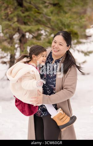 Madre e figlia condividono un momento di gioia nella foresta innevata di Tahoe Foto Stock