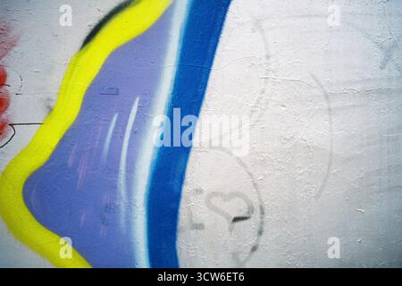 Struttura bianca della parete parzialmente coperta da murale. Ripresa con flash su pellicola analogica. Ogni crepa e pennellata rivelata. Studio delle superfici urbane. Foto Stock
