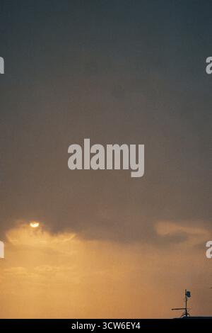 Nuvole a strati trafugate dalla luce soffusa del sole. Profondità nel cielo mentre il sole emerge tra le texture. Silenzioso e luminoso. Ripresa su pellicola analogica. Foto Stock