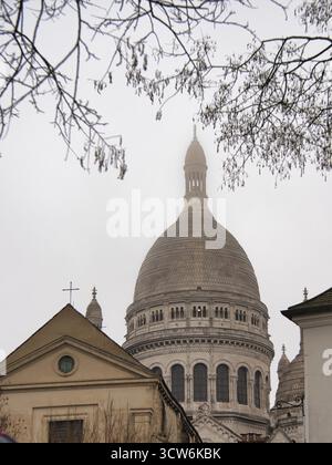 Basilica Sacré-Cœur nella nebbia parigina pesante - dettaglio architettonico ravvicinato di un edificio con la cupola principale e la croce della basilica del Sacro-Cœur disapp Foto Stock