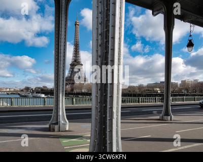 Vista della Torre Eiffel dal ponte Bir-Hakeim - la Torre Eiffel è stata caratterizzata in modo prominente su un cielo blu luminoso con nuvole bianche, incorniciata dal metallo grigio Foto Stock