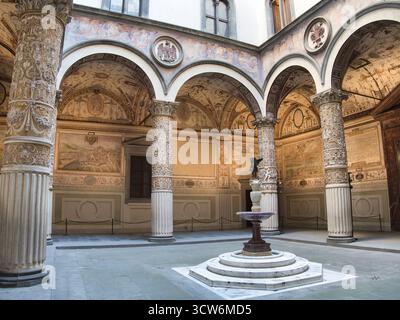 Cortile rinascimentale fiorentino con archi affrescati - storico cortile interno caratterizzato da colonne ornate, una fontana centrale e splendidamente affrescato Foto Stock