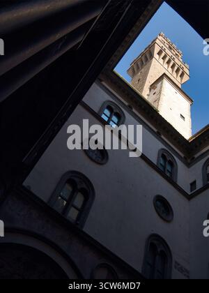 Vista della Torre di Palazzo Vecchio dal cortile scuro - spettacolare vista dall'angolo basso dell'iconica torre medievale di Palazzo Vecchio incorniciata dal buio, verti Foto Stock