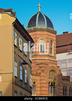 Storica cupola e croce della chiesa di Vienna - ornati in mattoni e iconica cupola di rame con una croce dorata su uno storico edificio ortodosso in basso Foto Stock