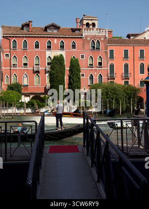 Taxi d'acqua di Venezia ormeggiati sul Canale - Una vista simmetrica di uno stretto molo in legno e due taxi d'acqua (motoscafi) ormeggiati in una cana veneziana residenziale Foto Stock