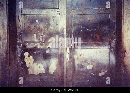 Vecchie porte di officina, macchiate e strisciate in astrazione. Il flash sulla pellicola scaduta rivela consistenza, tempo e composizione accidentale. Foto Stock