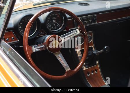 Interni di auto sportive italiane d'epoca - primo piano degli interni di un'auto d'epoca, con volante in legno, indicatori analogici e cruscotto con finiture in legno. Foto Stock