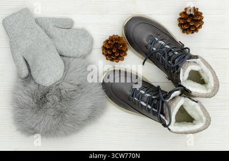 Un'immagine piatta e sopraelevata di un paio di caldi stivali invernali grigi con fodera in montone bianco, guanti in maglia grigia e collo in pelliccia sintetica grigio caldo Foto Stock