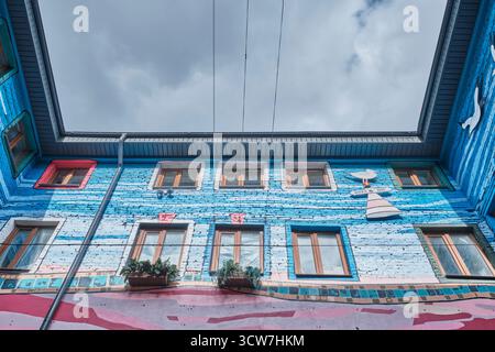 Saratov, Russia - 29 settembre 2025: Pareti in mattoni dai colori vivaci del cortile con affreschi artistici e finestre in legno. Edificio storico Blum. CRE Foto Stock