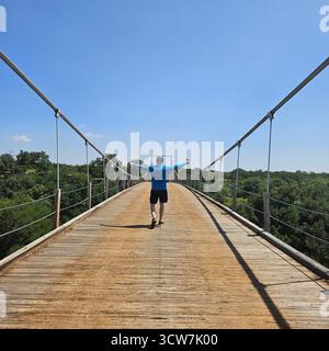 Un uomo sta camminando sul vecchio ponte sospeso a Regency, Texas Foto Stock