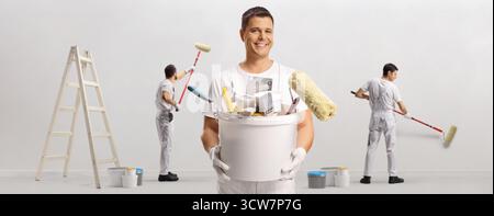 Squadra di pittori con un secchio di attrezzi e pennelli che dipingono un muro Foto Stock