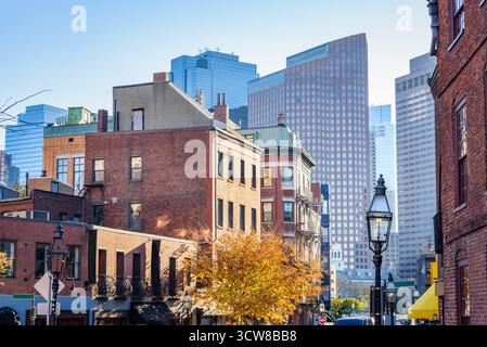 Tradizionali edifici residenziali in mattoni sovrastati da torreggianti grattacieli di uffici moderni a Boston al tramonto in autunno Foto Stock