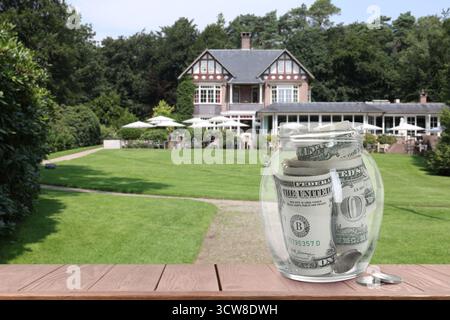 Barattolo con dollari e monete contro il condominio. Risparmiare denaro per comprare un appartamento Foto Stock