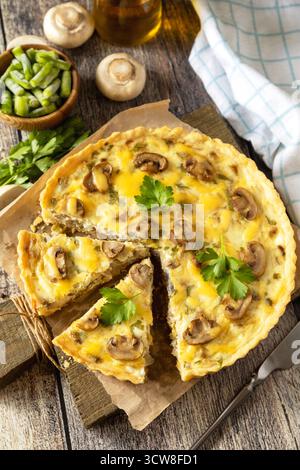 Deliziosa quiche di funghi fatti in casa con funghi e fagiolini su un tavolo rustico. Foto Stock
