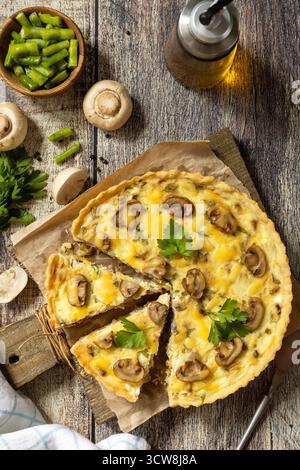 Deliziosa quiche di funghi fatti in casa con funghi e fagiolini su un tavolo rustico. Sfondo piatto della vista superiore. Foto Stock