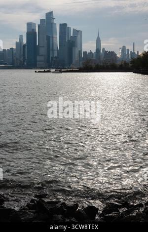 Gli alti grattacieli si riflettono sull'acqua calma, mostrando l'iconico skyline di New York alla luce del tardo pomeriggio. Foto Stock