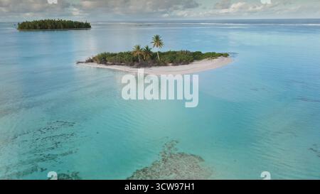 Questa scena mostra una splendida isola tropicale caratterizzata da spiagge sabbiose e lussureggianti palme, adagiate sullo sfondo di serene acque turchesi. Foto Stock