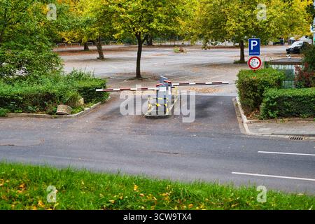 Ingresso al parcheggio con Barriera Gate nel Parco Autunno, circondato da vibranti alberi gialli e cespugli verdi con Clear Road e cartello di parcheggio Foto Stock