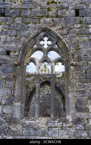 Traccia della finestra est della cattedrale di Kilmacduagh, con archi gotici oltre, monastero Kilmacduagh vicino a Gort, contea di Galway, Irlanda, in estate. Foto Stock