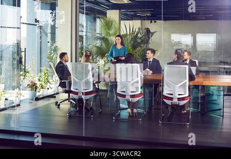 Gruppo di persone che lavorano per lavoro ascoltano il proprio collega, discutono di questioni lavorative nella sala conferenze. Foto Stock