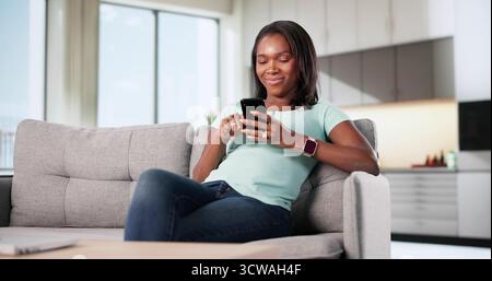 Donna gioiosa impegnata nella comunicazione online su dispositivi mobili Foto Stock