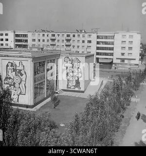 Una vista ad alto angolo cattura il Club 'October' di Sloviansk, RSS Ucraina, negli anni '1970, con i suoi grandi e suggestivi murales a mosaico. Un ottimo esempio di arte monumentale sovietica, i pannelli stilizzati sull'edificio modernista raffigurano temi del lavoro, della scienza e della cultura. Come Casa della Cultura per il quartiere industriale di Stroymash, il club sorge all'interno di un parco paesaggistico circondato da blocchi di appartamenti. Questa foto documenta un pezzo unico di arte e architettura pubblica dell'epoca sovietica Foto Stock