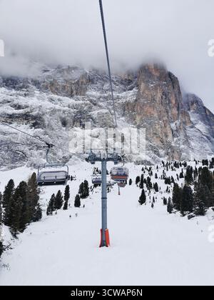 Le piste blu di Selva e Santa Cristina si estendono sotto le imponenti scogliere del Sassolungo, il Dolomiti Superski e il Sellaronda dell'alto Adige al suo meglio. Foto Stock