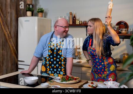Godetevi meravigliosi momenti di cucina insieme a grembiuli colorati, amici e Risate Foto Stock