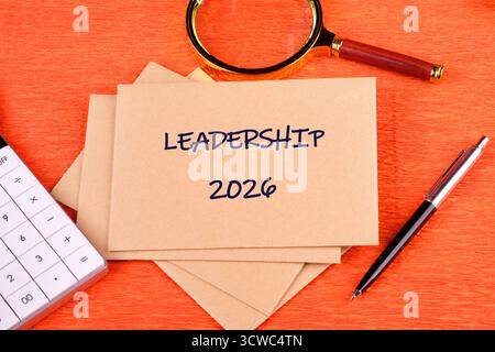 Una nota mostra Leadership e 2026. Si trova su una scrivania con una lente d'ingrandimento, una penna e una calcolatrice, indicando la pianificazione futura e le iniziative strategiche per Foto Stock