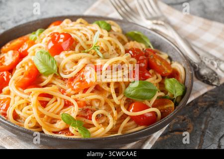 Spaghetti Margherita con pomodori ciliegini, olio d'oliva, burro, aglio, basilico fresco, mozzarella cremosa con un primo piano sul piatto del tavolo. orizzonte Foto Stock