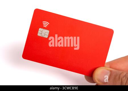 Mano con una carta di credito o di pagamento contactless di colore rosso brillante con chip e simbolo NFC Foto Stock