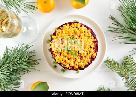 Insalata Shuba. Aringhe e aringhe sotto un cappotto di pelliccia. Insalata di verdure a strati di Natale con aringhe e verdure bollite su sfondo di legno bianco. Foto Stock