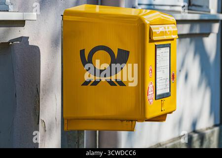 Contenitore postale Deutsche Post in colori di marca su un lato del muro di un edificio Foto Stock