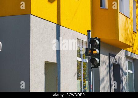 Le pareti dell'edificio dipinte a contrasto giallo e grigio sono illuminate dalla luce del sole e da un semaforo nelle vicinanze Foto Stock