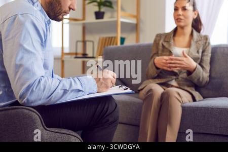 Psicoterapeuta che scrive appunti, sessione di psicoterapia, donna che parla con la sua psicologa. Foto Stock