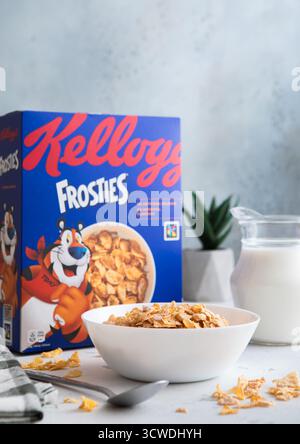 LONDRA, Regno Unito - 28 GIUGNO 2025: Cereali per la colazione Frosties flakes in piatto con cucchiaio e vasetto del latte sul tavolo della cucina. Foto Stock