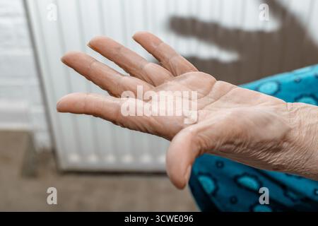 Primo piano di una donna anziana tesa la mano con la pelle rugosa. Foto Stock