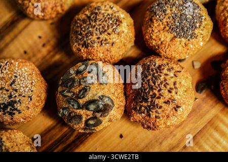 Panini a grani interi appena sfornati con vari semi come zucca, sesamo e lino su fondo in legno Foto Stock