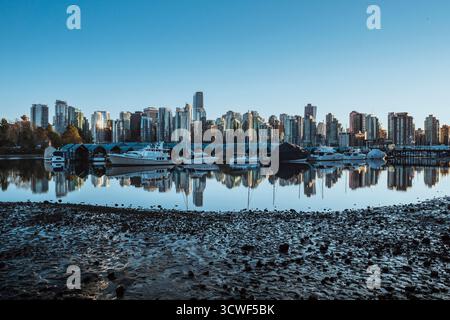 Gli alti edifici dello skyline della città si stagliano con orgoglio contro un cielo azzurro e si riflettono splendidamente nelle acque calme sottostanti al crepuscolo. Foto Stock