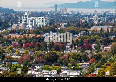 A Vancouver in autunno, le strade si animano con tonalità vivaci. Alberi vestiti di rosso e oro circondano case accoglienti, creando una scena pittoresca Foto Stock