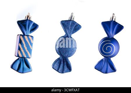 Decorazioni natalizie su sfondo bianco isolano - giocattoli di caramelle di vetro blu per l'albero di Natale. Decorazioni colorate a forma di caramelle in vetro blu Foto Stock