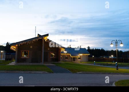 Altai, Russia - 13 maggio 2024: Veduta di due moderni Lodge in legno con tetti inclinati e luci decorative a corda lungo le gronde, illuminate dalla strada l Foto Stock