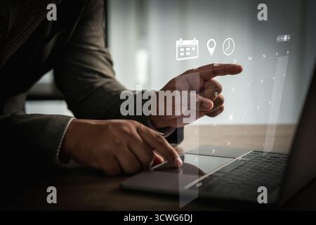 Calendario programma professionale uso di laptop con interfaccia olografica per pianificare programmi, fissare appuntamenti e gestire le scadenze Foto Stock