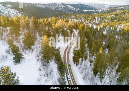 Una strada di montagna innevata con auto che la percorrono Foto Stock