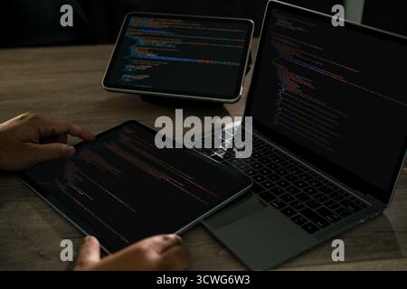 Programmatore che scrive il codice di progettazione del sito Web di sviluppo su una scrivania con spazio di lavoro scuro per laptop e tablet, tastiera manuale, css e html Modern software de Foto Stock